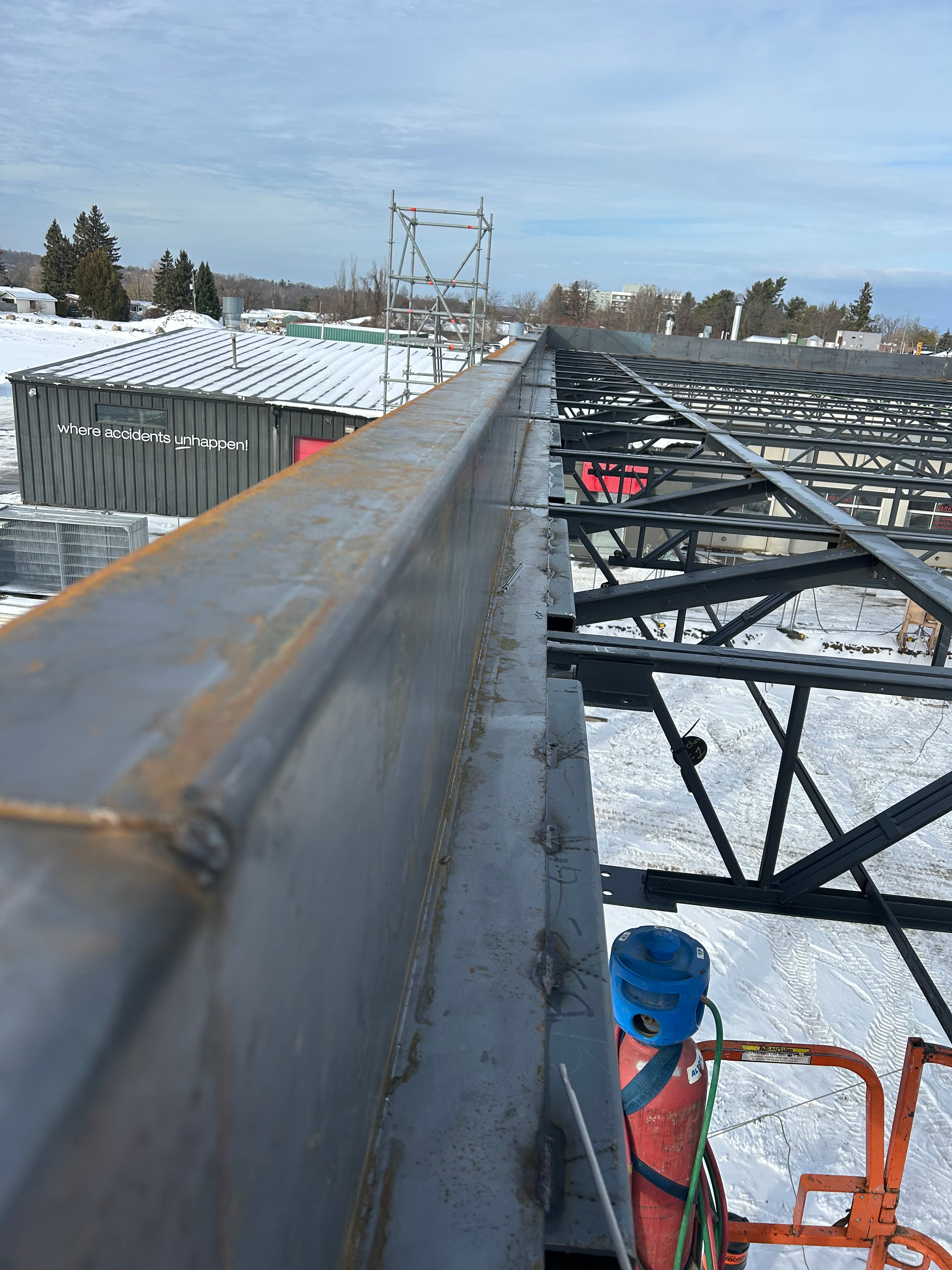Steel building framework under construction overlooking a snowy landscape from a high vantage point.